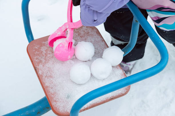 child makes snowballs with a plastic Snowball Maker. Active winter outdoor games.