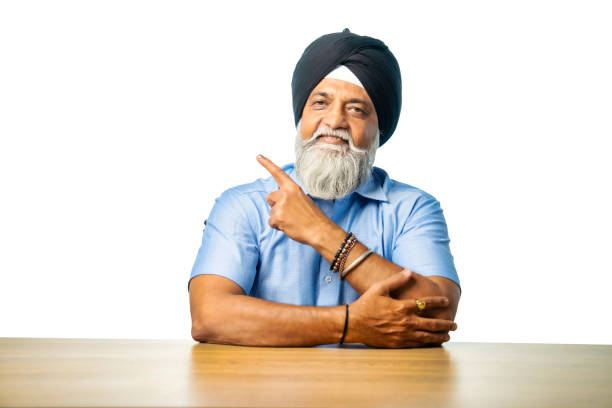 istock Sikh elderly man expressing emotions like thumbs up, pointing, or confusion at a table 2190322133