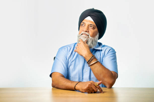 istock Sikh elderly man expressing emotions like thumbs up, pointing, or confusion at a table 2190322140