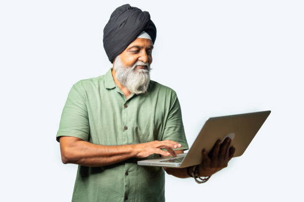 istock Indian Elderly Sikh man in casual wear using laptop while standing, showing confidence and success 2190322415