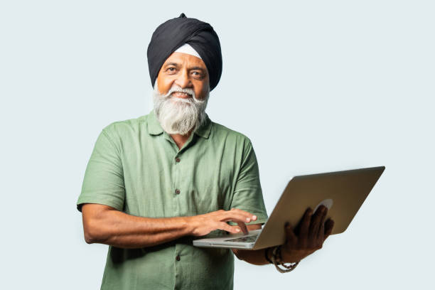 istock Indian Elderly Sikh man in casual wear using laptop while standing, showing confidence and success 2190322465
