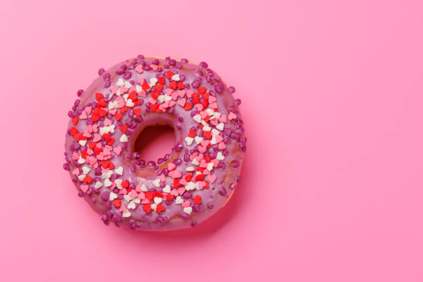 istock A sweet donut adorned with heart-shaped decor on a pink background 2190332252