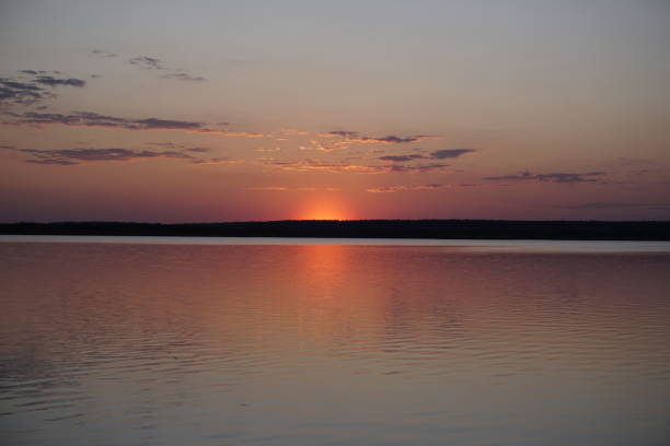 Quiet evening after a sultry day. Beautiful sunset over the lake. Reflection and horizon. Evening dim soft sun