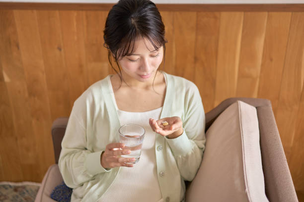 サプリメントとコップ一杯の水を持つ若い女性 - 薬  ストックフォトと画像