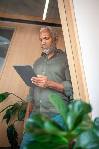 istock Confident Hispanic Senior Businessman Engages with Digital Tablet 2190342240