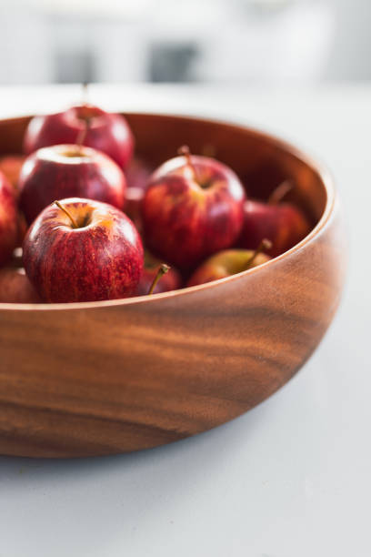 plenty of red apples in big wooden fruit bowl on kitchen countertop, concept of simple natural healthy ingredients