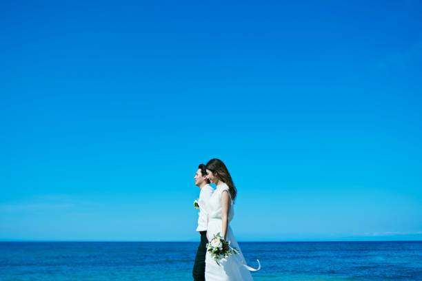 Groom carrying bride In arms at beach