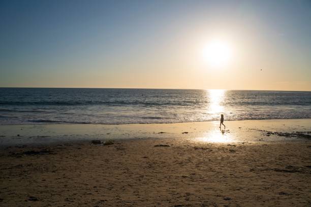 istock Serene beach sunset with lone figure on shoreline. 2190351567