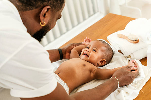 istock A joyful father interacts with his smiling baby during a tender moment on a changing table, fostering connection and playfulness. Happy diversity family and newborn bathing concept. 2190354556