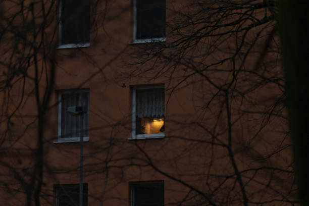 A building illuminated by a soft yellow light streaming through one of its windows, creating a warm glow against the night sky