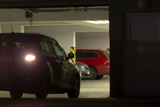 A car, possibly a luxury vehicle or family car, is parked in a garage during the nighttime hours, illuminated by automotive lighting