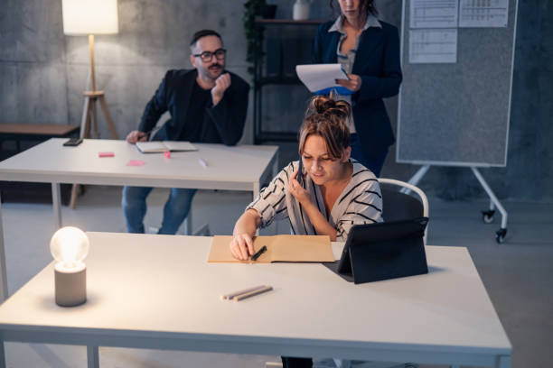 istock Businesswoman working late in office while talking on phone and taking notes 2190360209
