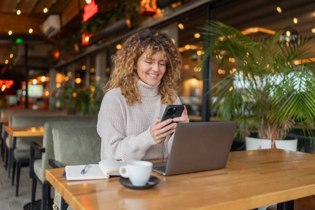 istock Happy female student sitting in a coffee shop, using a smartphone 2190360885