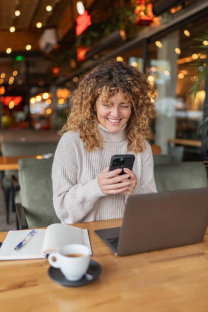 istock Happy female student sitting in a coffee shop, using a smartphone 2190360935