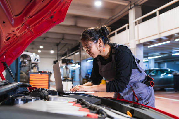 istock Young female mechanic using laptop while repairing car engine in garage 2190362172