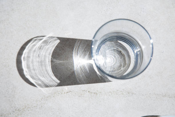 istock A clear glass of water is resting on a table and has a shadow on it 2190366683