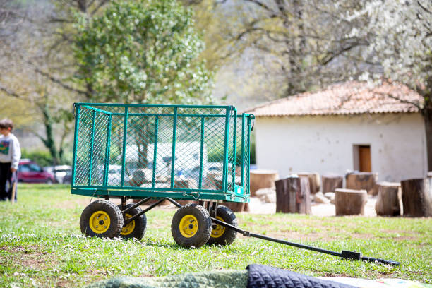 A green wagon that features bright yellow wheels is parked in the middle of a lush, grassy field, enjoying the serene outdoors