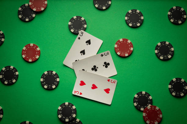 istock Three threes or a combination of playing cards three of a kind, set. Winning chips and cards for playing poker are scattered chaotically on a green table 2190372703