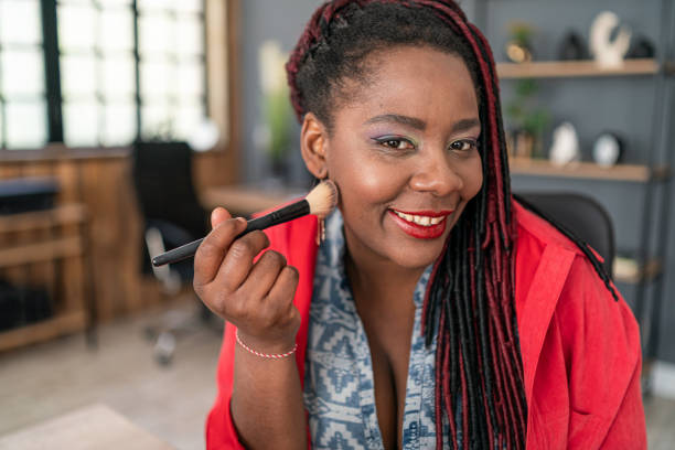 istock African american woman using blush brush doing her makeup 2190376910
