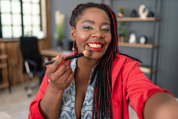 istock African american woman using blush brush doing her makeup 2190376915