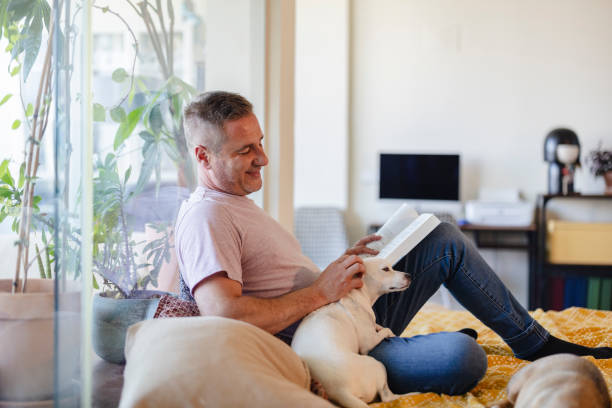 istock Man reading a book and petting his dog at home 2190378696