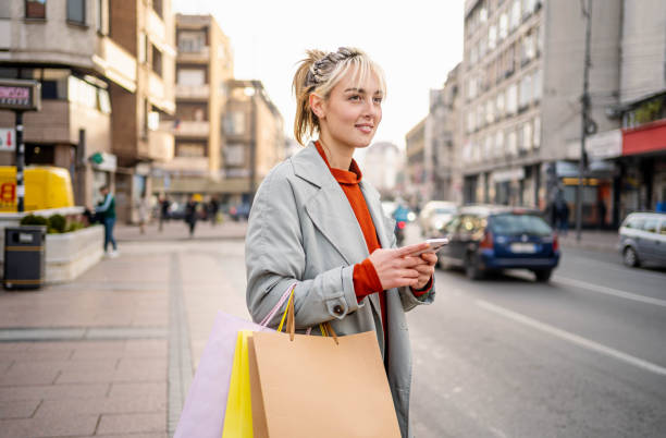 istock Woman using a mobile phone and carrying shopping bags 2190380087