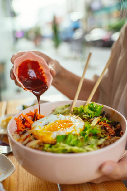 Woman adding sauce to his Bi Bim Bap