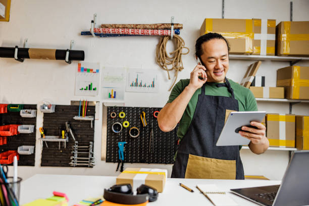 istock Smiling Chinese man talking on the phone with customer in retail place 2190383508