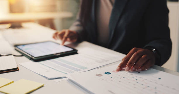 istock Person hands, tablet and documents in office for business, financial planning and data analysis at night. Woman, tech or paper with graphs for growth projection, company development or audit deadline 2190386154