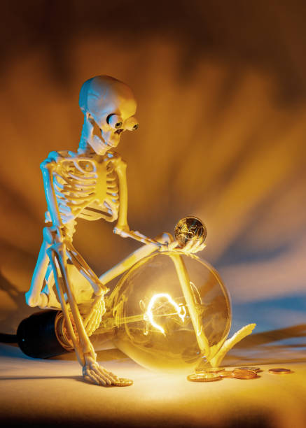 A large bulb shining with golden light and a sad skeleton looking at euro coins.