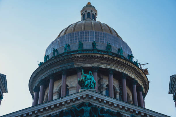 Close-up of the dome of St. Isaacs Cathedral in St. Petersburg, Russia, featuring sculptures and columns. The image highlights the architectural and cultural grandeur of this historic landmark