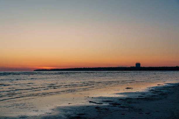 Serene beach scene at sunset with gentle waves and a calm horizon, creating a peaceful atmosphere with soft twilight colors reflecting on the wate
