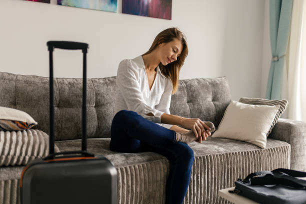 Woman moving into a new apartment Mid-adult woman moving into a new apartment. She is sitting on the sofa and massaging her foot, she is tired. travel Foot Fatigue stock pictures, royalty-free photos & images