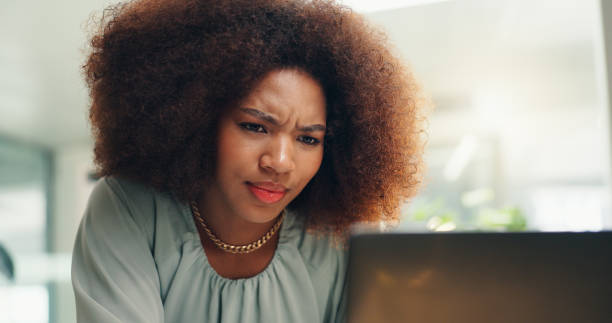 istock Business woman, laptop and doubt for press release with problem solving and confused in office. Website, publicity worker and African professional with idea, reading and planning for web project 2190395451