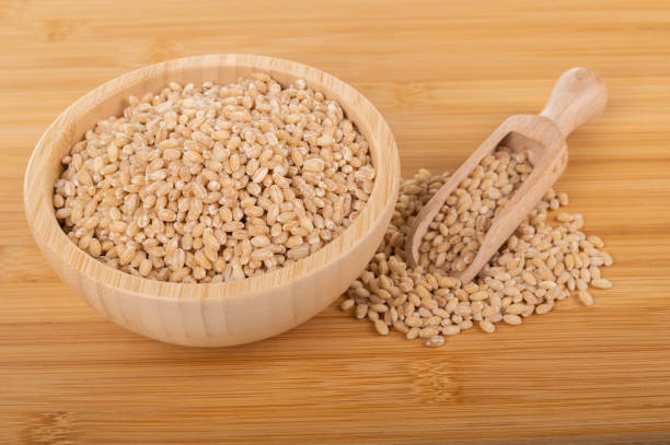 istock Pearl barley in a wooden bowl with a scoop on a bamboo surface 2190396171