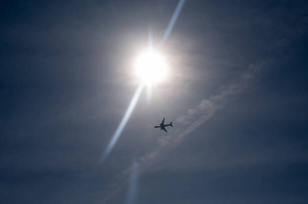 An airplane from below with lots of sky and bright sun