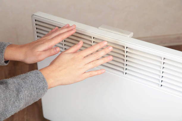 istock Young woman warming hands near modern electric heater. Space for text 2190403686