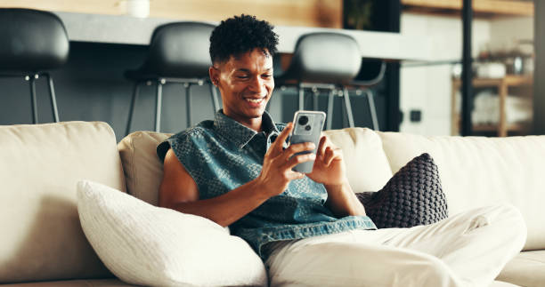 istock House, relax and man on sofa, smartphone and typing with social media, connection and network. Apartment, person and guy on couch, cellphone and message to contact, digital app and texting in lounge 2190405352