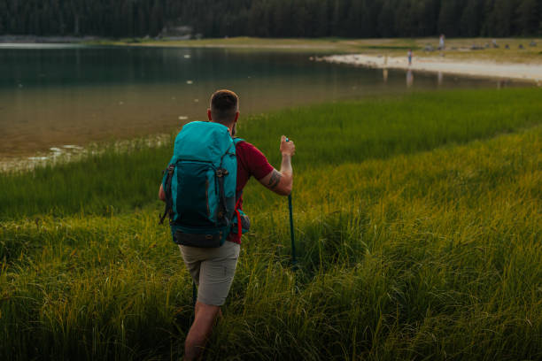 istock Man hiking on a grassy shore of a lake 2190409379