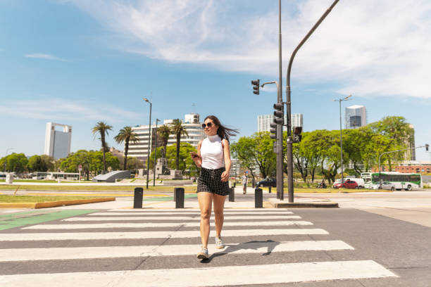istock Woman using smartphone crossing the street 2190411096