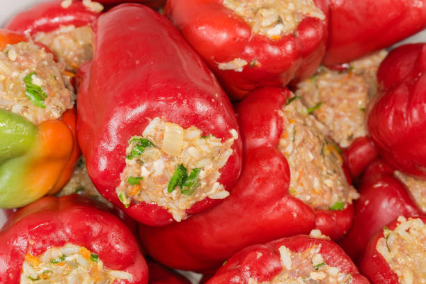 Heap of raw bell pepper stuffed with rice and chopped meat, which requiring final cooking, close-up in selective focus