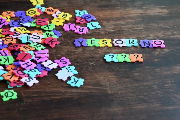 Colorful puzzle pieces with letters and symbols on a wooden table, forming the words 'YES OR NO' and '???'.