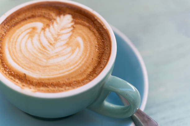 High angle view of a cup of hot latte coffee with plant shape on surface