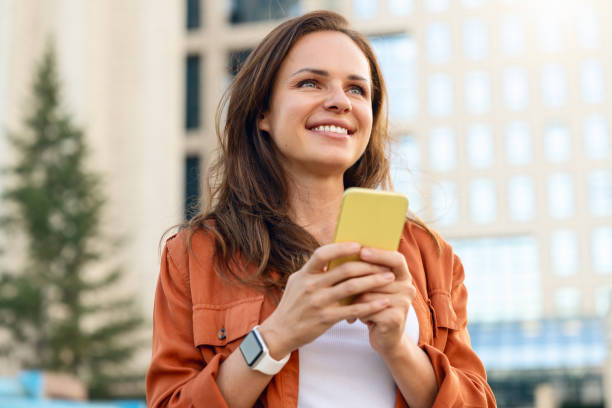 istock Caucasian brunette woman using her smartphone while standing on city street. 2190416213