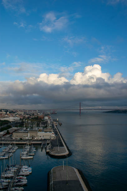 Aerial view of lisbon cityscape with 25 de abril bridge over tagus river under cloudy sky