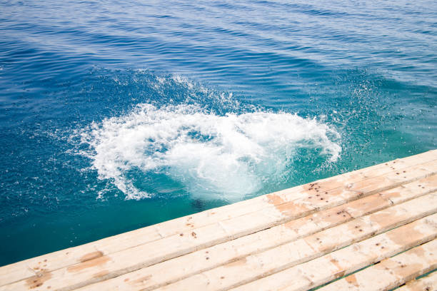 Middle age man enjoying on summer vacations in Greece. He jumping from cliff and diving into blue sea