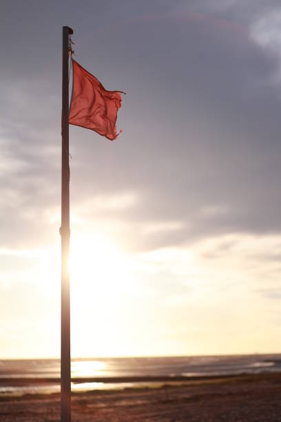 istock Red flag is flying on a pole in front of a cloudy sky 2190426073