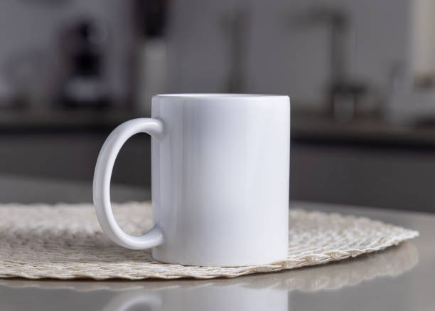 istock Closeup of  white blank coffee mug on grey kitchen table over blured kitchen interior, mockup 2190427292