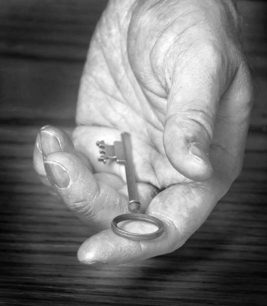 istock Old Rough Hand Holding Old Key Giving Away Knowledge Key to Success 2190430896