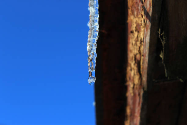 After a frosty night, the sun melts the snow in the morning and icicles appear on the edge of the roof.